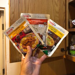 a hand holding three packets of food