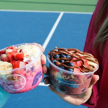 Surf Bar - a woman holding two bowls of food - Acai Bowls Near Me - Edmond, Oklahoma