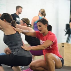 Crossfit Mudtown - Coach Jacki Rodgers instructs CrossFitter on proper squatting form
