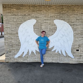 Beer Lab - Ghostface Brewing - a woman leaning against a brick wall with angel wings painted on it - Breweries Near Me - Mooresville, North Carolina