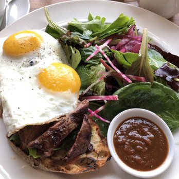 Mildred's Temple Kitchen - The Manhandler: sliced flat iron steak on toasted garlic sourdough, two sunny side up eggs with arugula. - Breakfast & Brunch Near Me - Toronto, Ontario Mildred's Temple Kitchen - The Manhandler: sliced flat iron steak on toasted garlic sourdough, two sunny side up eggs with arugula. - Breakfast & Brunch Near Me - Toronto, Ontario