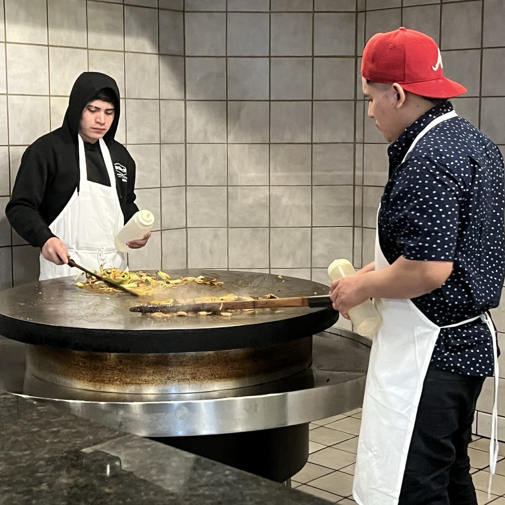The cooks circling around the Mongolian style grill. The cooks circling around the Mongolian style grill.
