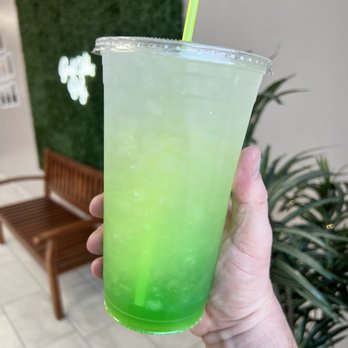 New Level - a hand holding a green drink - Juice Bars & Smoothies Near Me - Kearney, Nebraska