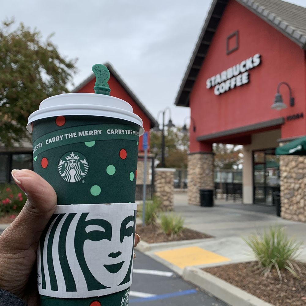 a starbucks cup in front of a starbucks coffee shop