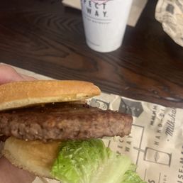 a hand holding a hamburger and lettuce