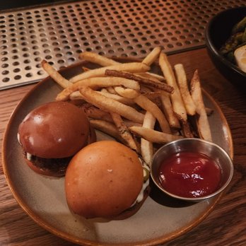 The Lobby - Sliders and fries - A plate with French fries, two sliders with buns, and a small container of ketchup on a wooden table. - Bars Near Me - Brooklyn, New York