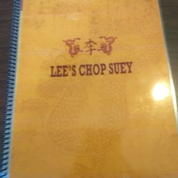 Menu front - The image shows a menu cover from Lee's Chop Suey, a Chinese-American restaurant located in Chicago, IL. The cover is spiral-bound with a yellow background, displaying Chinese characters and the restaurant's name in bold, dark red letters. The design includes subtle dragon motifs in the background, emphasizing traditional Chinese elements.