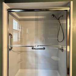 Shower remodel with sliding glass doors and grab bars for extra safety.