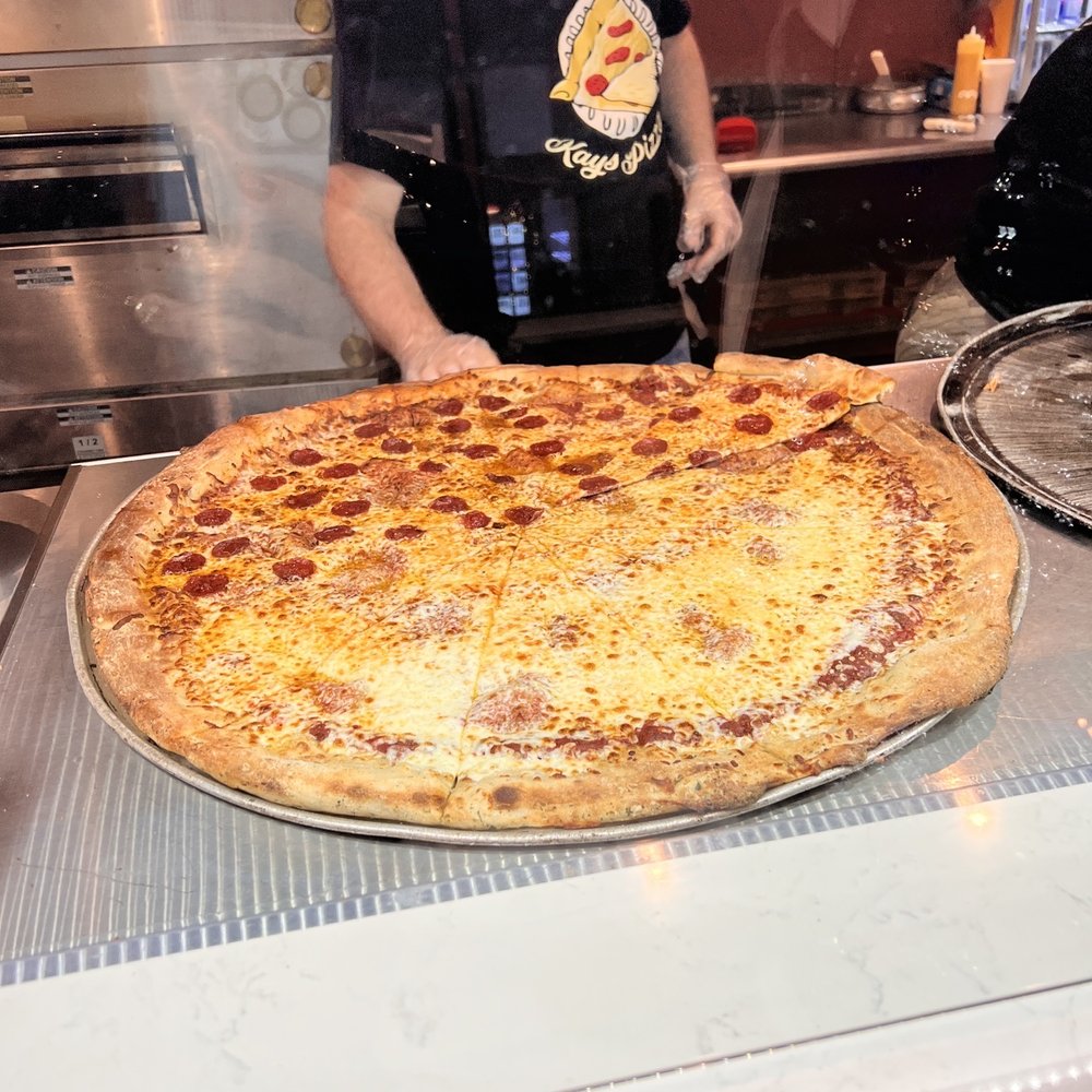 a man in a kitchen with a large pizza a man in a kitchen with a large pizza
