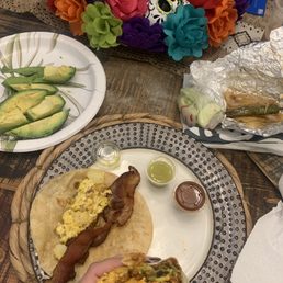 Chorizo egg and potato burrito with avocado and a bacon egg and potato taco, grilled onions and taco on the side Chorizo egg and potato burrito with avocado and a bacon egg and potato taco, grilled onions and taco on the side
