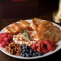 The Whisper House - Try our Baked Brie! House Made Hot Honey, Raspberries, Strawberries, Blueberries, and Candied Walnuts with Toasted Crostini Bread