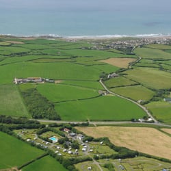 Budemeadows Touring Park - Our Cornish Campsite seen from the air looking towards the sand and surf at Widemouth Bay