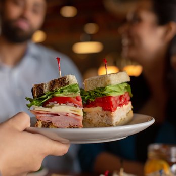 Wildflower - a person holding a plate with a sandwich on it - New American Near Me - Flagstaff, Arizona