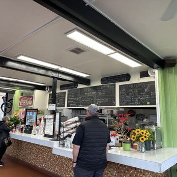 By's - a man standing at a counter in a restaurant - Burgers Near Me - Seattle, Washington By's - a man standing at a counter in a restaurant - Burgers Near Me - Seattle, Washington