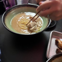 Plain Ramen - A bowl of ramen with broth, noodles, and a piece of meat, with a person using chopsticks to pick up the meat.