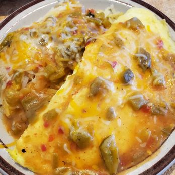 Weck's - A close-up of a breakfast dish showing a cheese omelette topped with chopped green peppers. The omelette appears fluffy with melted cheese visible on top. The dish is served on a ceramic plate, with a portion of hash browns or potatoes partially visible in the background. The setting suggests a casual dining environment, likely at a restaurant or diner. - Breakfast & Brunch Near Me - Santa Fe, New Mexico