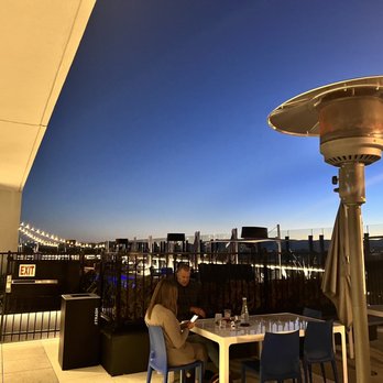 Kisbee on the Roof - a woman sitting at a table - Bars Near Me - Denver, Colorado