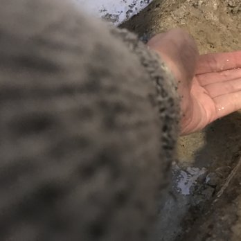 Girls 'n' Tools - A person's hand with water on it is visible, positioned near a muddy or dirt-covered surface, possibly in an outdoor or construction setting. - General Contractors Near Me - Danielson, Connecticut