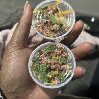Outback Steakhouse - ALLL that bacon I never wanted contaminating my chives and cheese. Awesome! - A person with dark skin holds two small, clear plastic containers filled with chopped meat, green onions, and possibly other ingredients. The containers are held in one hand, with a blurred background that appears to be indoors, possibly in a casual setting. The containers contain food ingredients, suggesting they are part of a meal or snack, with visible green onion pieces and meat bits. - Steakhouses Near Me - Dover, Delaware
