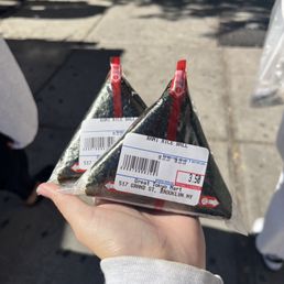 a person holding a package of sushi a person holding a package of sushi