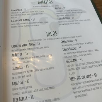 Comomango - A photograph of a menu page from Comomango restaurant in Madison, CT, displaying sections for burritos and tacos. The menu includes items such as California Burrito, Veg Out, Chicken Street Tacos, Al Pastor, Carnitas, and others, with detailed descriptions of ingredients and prices. The menu emphasizes traditional Mexican flavors and modern twists, with options for various dietary preferences. - Mexican Near Me - Madison, Connecticut