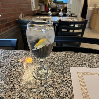 Eggs & Thai Café - Nice clean interior - A clear glass of water with a lemon slice is placed on a granite table in a restaurant, with a background of chairs, a TV, and decorative elements. - Thai Near Me - Dedham, Massachusetts