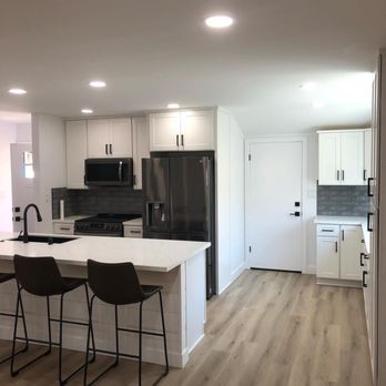 Blue Line Builders - a kitchen with white cabinets and black appliances - General Contractors Near Me - Santee, California