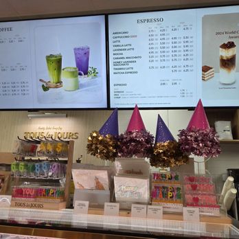 Tous Les Jours Bakery and Cafe - Counter - Digital menu board at Tous Les Jours Bakery and Cafe showing coffee, tea, and espresso prices, along with images of drinks and awards. - Bakeries Near Me - Tysons, Virginia