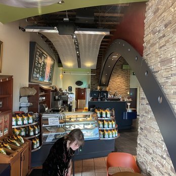 Satellite Coffee - Looking inside - A coffee shop interior featuring a counter with display cases, menu boards on the wall, and a customer seated at a table. - Coffee & Tea Near Me - Albuquerque, New Mexico