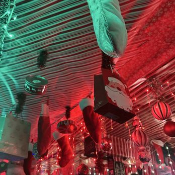 River - Decorations include Christmas stockings, red and green ornaments, and a Santa-themed gift bag hanging from a ceiling with red and green lighting. - Bars Near Me - Denver, Colorado