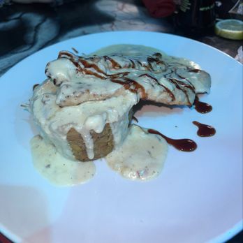 Vaka Restaurant - main menú - A dessert on a white plate includes a cake topped with cream, drizzled with chocolate sauce, and garnished with a piece of pastry. - Sushi Bars Near Me - Lawrence, Massachusetts
