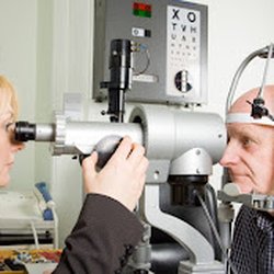 Specialty Eye Institute - Women eye doctor checking old mans eyes