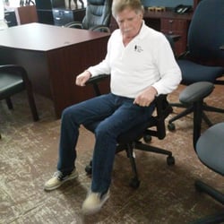 Office Furniture Place - Owner demonstrating chair for sale.