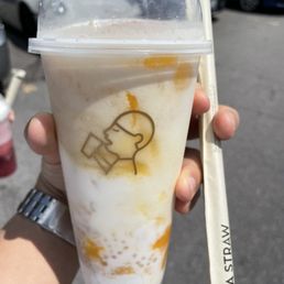 A person holds a large plastic cup with a beverage from HEYTEA in Toronto, ON, featuring a logo of a person drinking from a cup.