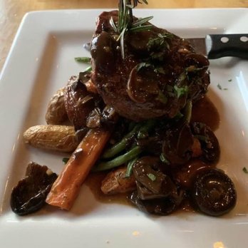 Loon Lodge - Sirloin with root vegetables - A dish with a piece of meat topped with herbs, served with root vegetables and mushrooms on a white plate. - Bed & Breakfast Near Me - Rangeley, Maine