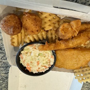 Long John Silver's - A takeout meal with fried chicken, waffle fries, coleslaw, hush puppies, and a fish fillet in a cardboard box on a granite countertop. - Seafood Near Me - Clovis, California