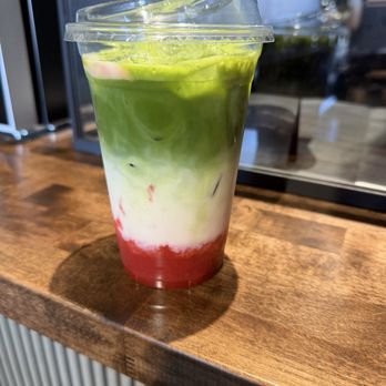 Cotta Nostra - Strawberry Matcha - A multi-layered beverage in a clear plastic cup features green, white, and red sections, likely a matcha-based drink with fruit syrup. - Coffee & Tea Near Me - Phoenix, Arizona