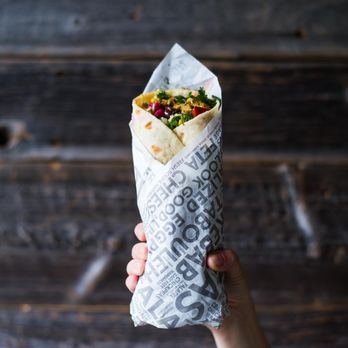 Mezeh - a hand holding a burrito wrapped in paper - Halal Near Me - Richmond, Virginia