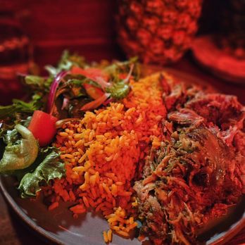 Papi - a plate of food on a table - A plate of Puerto Rican cuisine featuring rice, shredded meat, and a side salad, with a drink and basket in the background, set in a restaurant. - Cocktail Bars Near Me - Portland, Maine