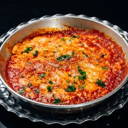 Persian Omelette - a fan favorite.  Scrambled eggs mixed into a rich tomato base, garnished with parsley served with our homemade bread.