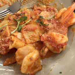 Paepadel and vodka sauce with shrimp. Absolutely delicious! - A plate of pasta with shrimp, coated in tomato sauce, garnished with microgreens, and served in a restaurant. The dish appears freshly prepared with visible pasta, shrimp, and sauce, presented on a ceramic plate.