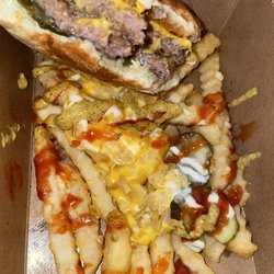 MrBeast Burger - Chomped half Beast burger perched inside container of Beast style fries