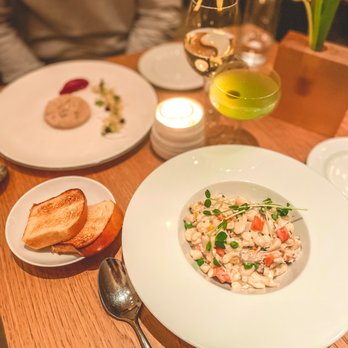 Wallsé - a table with plates of food and a glass of wine - Austrian Near Me - New York, New York Wallsé - a table with plates of food and a glass of wine - Austrian Near Me - New York, New York