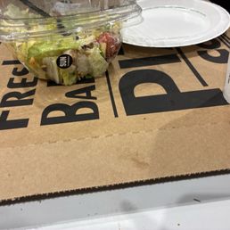 Pizza box, Caesar salad, and a soda