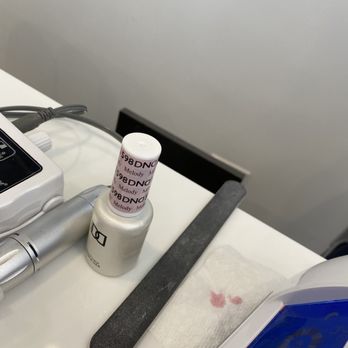 Vip Nail Spa - A nail polish bottle, a nail file, and manicure tools are arranged on a white surface, with a paper towel nearby. - Nail Salons Near Me - Chicago, Illinois