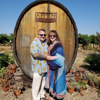 Coche Vino Wine Tours - a couple standing in front of a barrel - Wine Tours Near Me