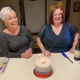 two women sitting at a table with a cake