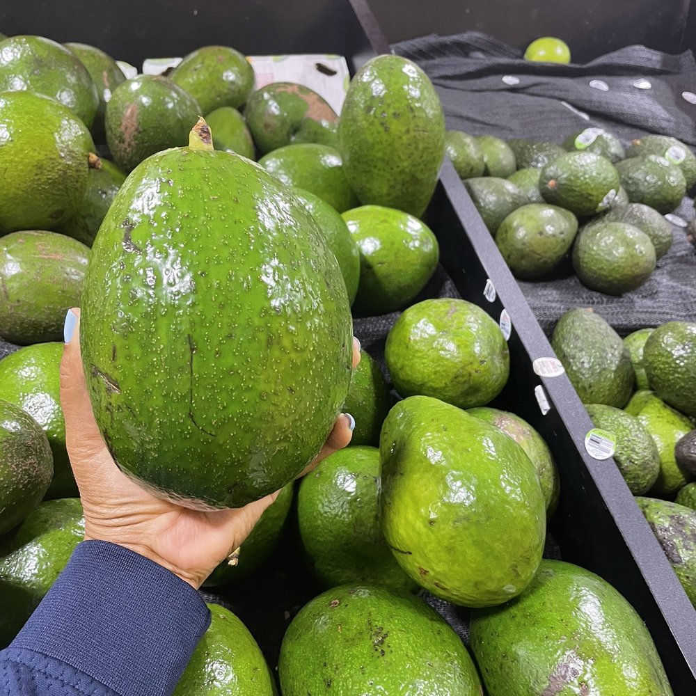 Bravo Supermarket - a person holding an avocado - Grocery Near Me - West Palm Beach, Florida