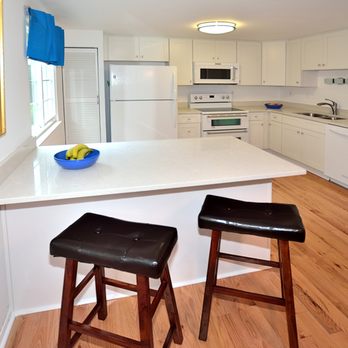 Floor & Design - a kitchen with white cabinets, a counter, and two stools - Flooring Near Me - Ashburn, Virginia Floor & Design - a kitchen with white cabinets, a counter, and two stools - Flooring Near Me - Ashburn, Virginia