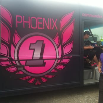 Phoenix - a woman standing in front of a pink and black bus - Food Trucks Near Me